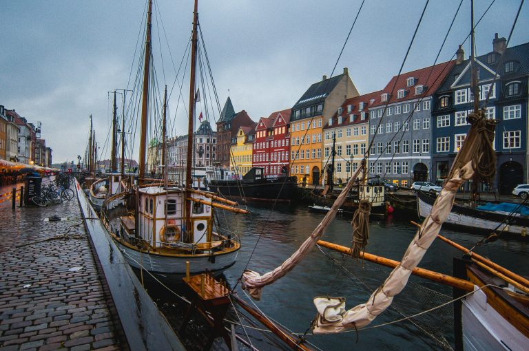 Vibrant Nyhavn harbor in Copenhagen with docked boats against colorful historic buildings.